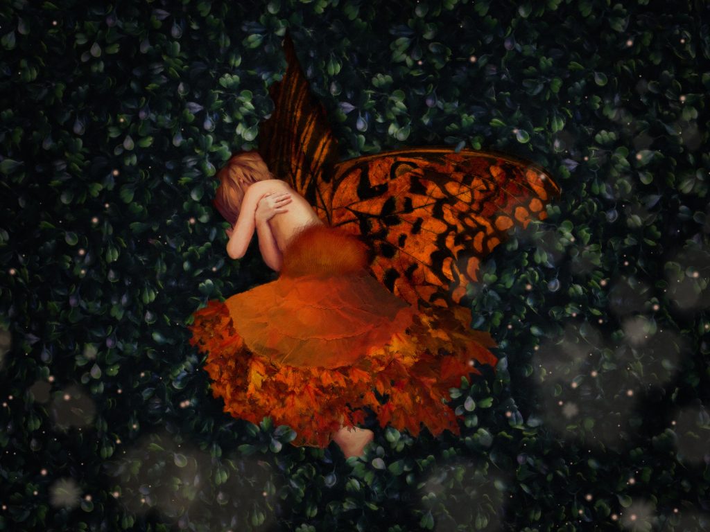 a fairy like an autumn maple leaf, laying in grass